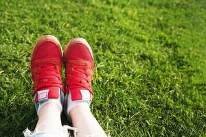 female legs in sneakers on a background of green grass photo