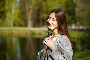 Portrait of a girl on the background of a Park with a lake, holding a wild forest flower. photo