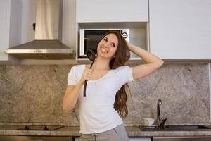 Woman singing in the kitchen with a ladle photo