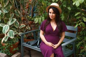 happy pregnant woman in a straw hat  sits on a bench in a Park photo