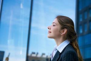 The girl stands sideways against the background of business centers. photo