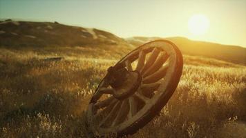 Old wooden wheel on the hill at sunset photo