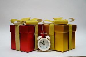 Gift boxes and alarm clock on light background photo