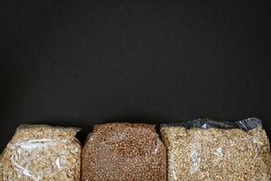 packs of buckwheat oatmeal and pearl porridge on a black background photo