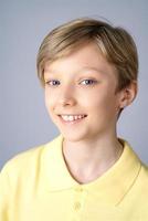 Portrait of cute boy in yellow t-shirt, blond hair smiling on white background, photo
