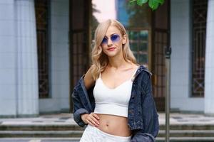 mujer joven posando en la calle de la ciudad en un chándal y gafas de sol foto