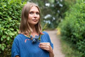 Portrait of beautiful woman with blue eyes in blue dress is standing on a path photo