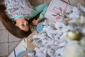 una joven morena en un interior festivo cerca del árbol de navidad. foto