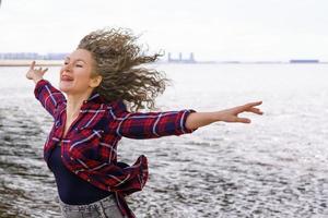 Woman with outstretched arms to the side against the background of water photo