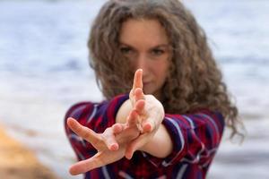 Close-up portrait of a woman dancing on the beach, hands in front of her in the frame photo