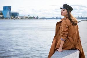 Sad lonely woman sitting on the embankment of the river photo