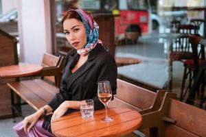 hermosa mujer se sienta en un café de la calle con una copa de vino foto