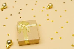 Christmas gift box with golden ribbon and bow on yellow background photo