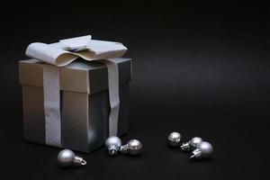 Silver gift box with christmas balls on black background photo