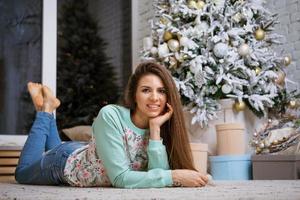 young woman lies on the floor by the christmas tree photo