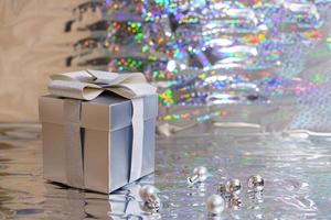 Silver gift box with christmas balls on shiny background photo