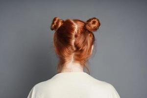 back view of red-haired woman with space buns hairstyle photo