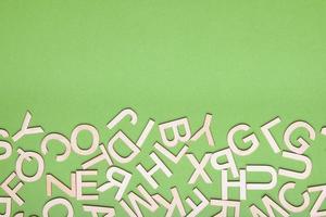 mezcolanza de letras de madera sobre fondo de papel verde foto