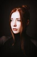 glamor portrait of elegant young lady with long red curtain bangs and black dress photo