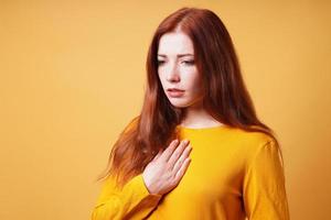 sad young woman with hand on chest feeling heartache or heartburn photo