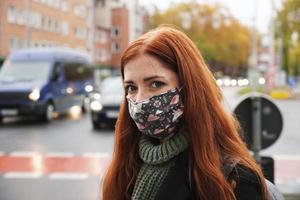 young woman wearing everyday cloth face mask outdoors in city raffic photo