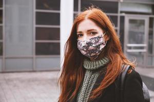 young woman wearing everyday cloth face mask outdoors in city photo