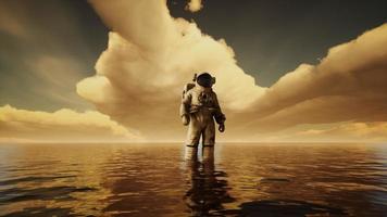 Spaceman in the sea under clouds at sunset photo