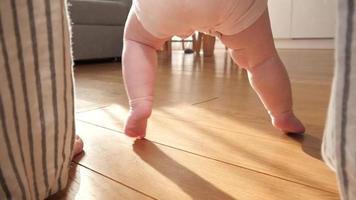 la madre enseña al bebé a caminar en casa - piernas diminutas en el suelo
