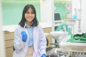 mujer dentista sosteniendo una sonda dental y un espejo revisando al paciente en la clínica dental, control de dientes y concepto de dientes sanos foto