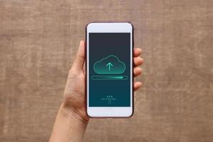 Smartphone on hand opening cloud uploading concept on phone screen. woman or man hand upload from mobile phone to store data on server photo
