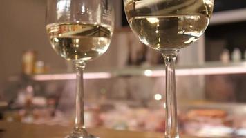 un homme et une femme prennent un verre de vin blanc de la table à l'intérieur d'un magasin viticole video