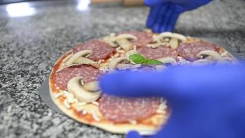 en kock förbereder en pizza med tomat, mozzarella och salami video