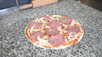 een kok bereidt een pizza met tomaat, mozzarella en salami video