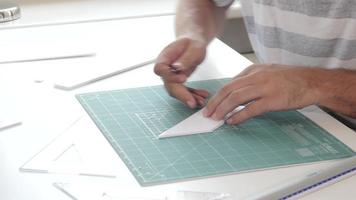 les mains de l'homme de concepteur d'architecture travaillent avec un modèle sur la table, coupant une plaque de mousse video