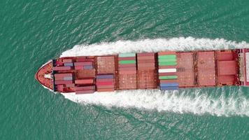 Aerial top view of cargo maritime ship with contrail in the ocean ship carrying container and running for export  concept technology freight shipping by ship smart service video