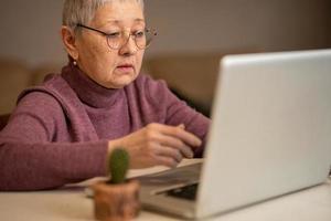 woman sitting in front of laptop communicates online through social networks. Selective focus photo