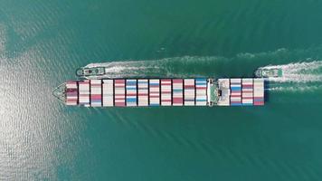 Luftaufnahme des Frachtschiffs mit Container und Betrieb mit Schlepper für Exportgüter vom Frachthafen zum benutzerdefinierten Ozeankonzept Frachtversand per Schiff. video
