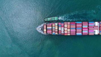 Luftaufnahme des Frachtschiffs mit Container und Betrieb mit Schlepper für Exportgüter vom Frachthafen zum benutzerdefinierten Ozeankonzept Frachtversand per Schiff. video