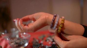 vrouwenhanden werken met koralen om koraalarmbanden op tafel te maken video