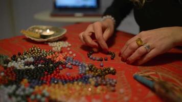 les mains des femmes travaillent avec des coraux pour fabriquer des bracelets de corail sur une table video