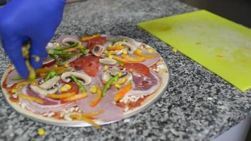 un cocinero prepara una pizza con tomate, mozzarella y salami video