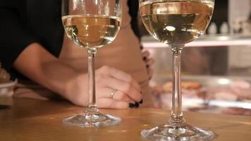 een man en een vrouw nemen een glas witte wijn van de tafel in een wijnwinkel video