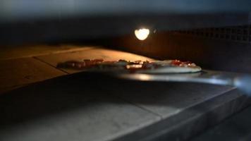 Ein Koch legt Pizza in den Ofen video