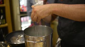 un cuisinier met du sel dans une eau bouillante dans une cuisine de restaurant video