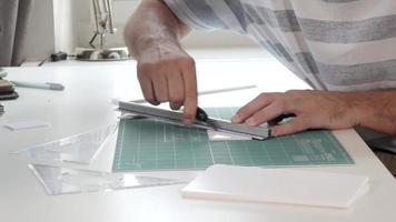 les mains de l'homme de concepteur d'architecture travaillent avec un modèle sur la table, coupant une plaque de mousse video