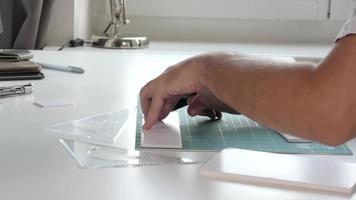 mãos de homem de designer de arquitetura trabalham com um modelo na mesa, cortando uma placa de espuma video