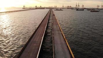 Aerial view of Bridge for export import cargo to crane at sun set , Bride road to international cargo dock sea port. video