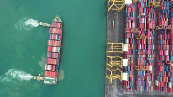 vista aérea del arrastre de un buque portacontenedores en un remolcador hasta el concepto de puerto de la terminal internacional envío de mercancías por buque video