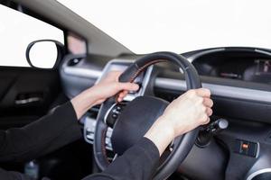 Hand holding steering wheel in modern private car with blank windshield photo