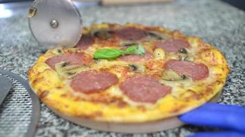 um cozinheiro corta uma pizza quente fresca em pedaços em uma cozinha video